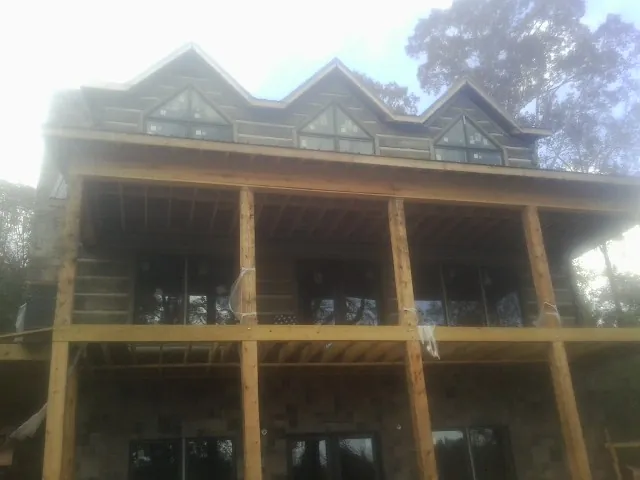 Dormers and porch framing on a large log home under construction — Roof Coating work by our crew in Pearl River