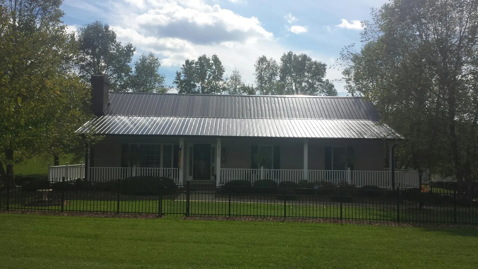 Gray metal roof on a brick ranch with a full width front porch — Gutter Guard Installation work by our crew in Pearl River